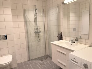 Ein modernes Badezimmer mit einer Duschkabine, einem weißen Waschbecken und einer Toilette.