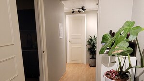 A hallway with wooden flooring, white walls, and a potted plant on the right. - Apartment with sea and mountain view (Bergen)