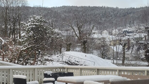 A patio with wicker furniture and a view of a snow-covered landscape. - Apartment with sea and mountain view (Bergen)