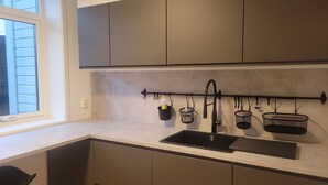 A kitchen with a double sink, cabinets, a window, and a black utensil rack. - Apartment with sea and mountain view (Bergen)