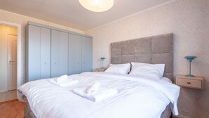 A bedroom with a large bed, a wardrobe, bedside tables, and a hanging light fixture. - Holiday house with perfect location (Vestvågøy)