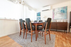 Un comedor con una mesa de madera, sillas negras, un tapete, un aparador de madera y obras de arte en la pared.
