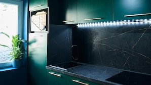 A modern kitchen with green cabinets, a black countertop, and a built-in oven.