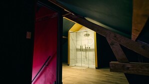 A room with a wooden ceiling and a glass shower enclosure.