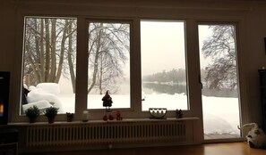 A room with three large windows, a radiator, and various small items on the windowsill.