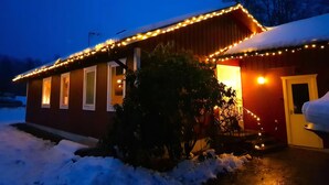 Lumipeitteinen katto ja kuisti, jotka on valaistu koristeellisilla valonauhoilla.