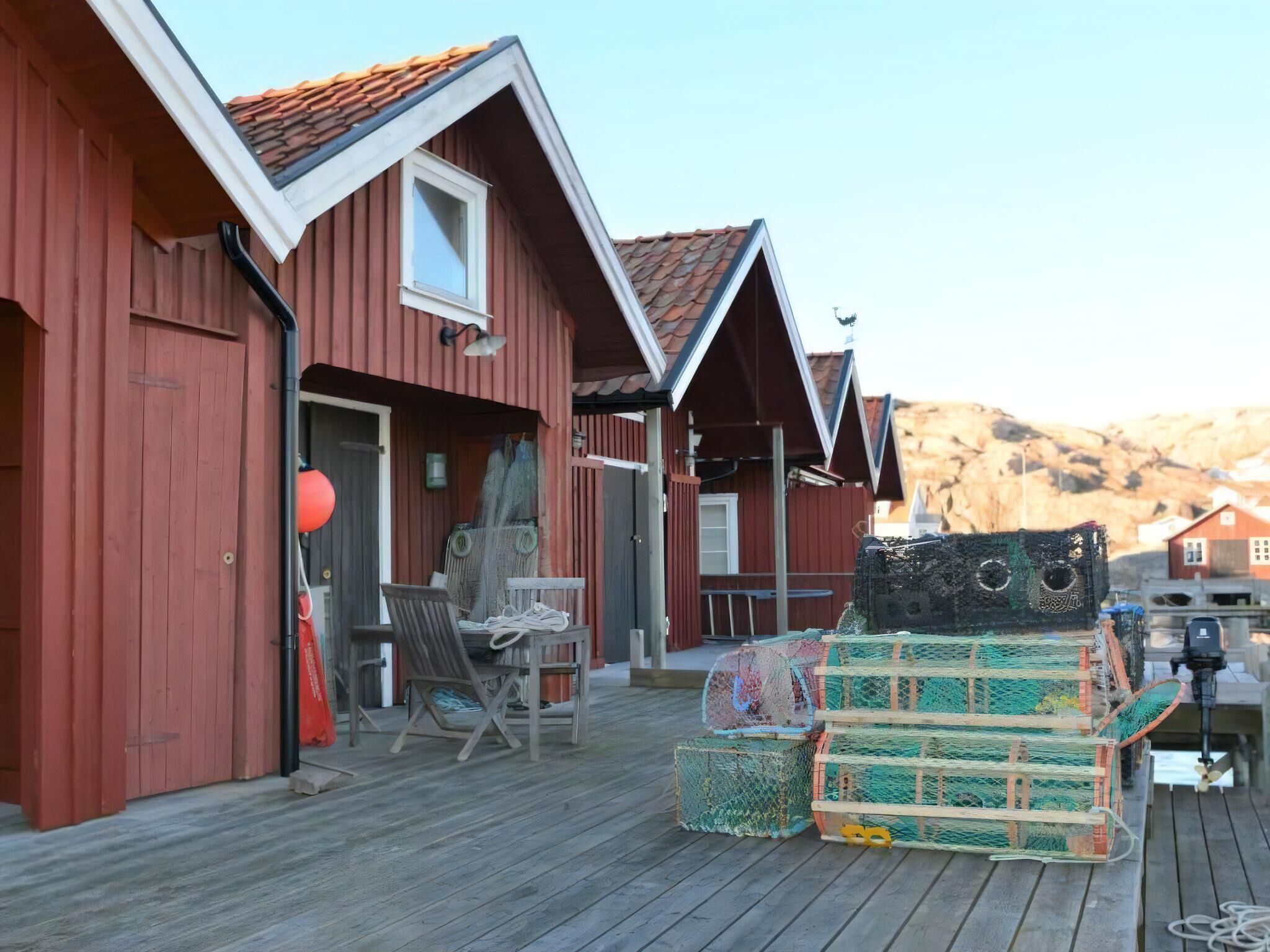 Une terrasse en bois avec un bâtiment rouge, une chaise et des caisses empilées.