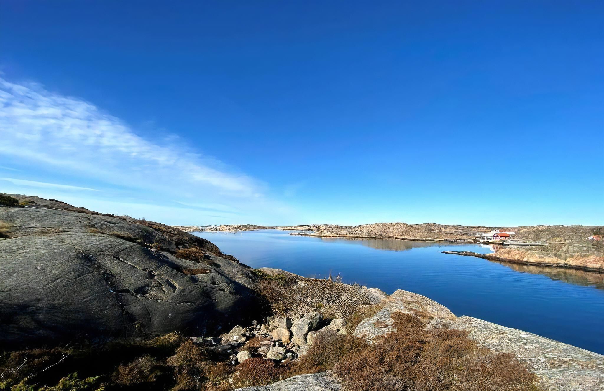 A lake with a rocky shoreline and a small building with a red roof.