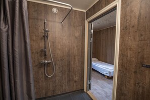A shower with a handheld showerhead, a wall-mounted faucet, and a shower control panel.
