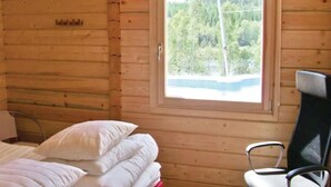 A cabin with a bed, pillows, a chair, and a window with a forest view. - Large holiday home with beautiful view of Nässjön (Gislaved)