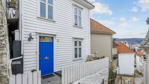 En vit byggnad med en blå dörr, en liten veranda och ett vitt trästaket.