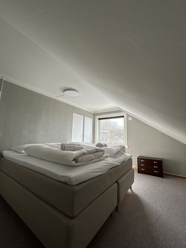 Un dormitorio con cama, cómoda y ventana.
