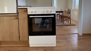 Eine Küche mit einem weißen und schwarzen Electrolux-Ofen, Holzausbau und einem Essbereich mit Stühlen und einem Tisch.