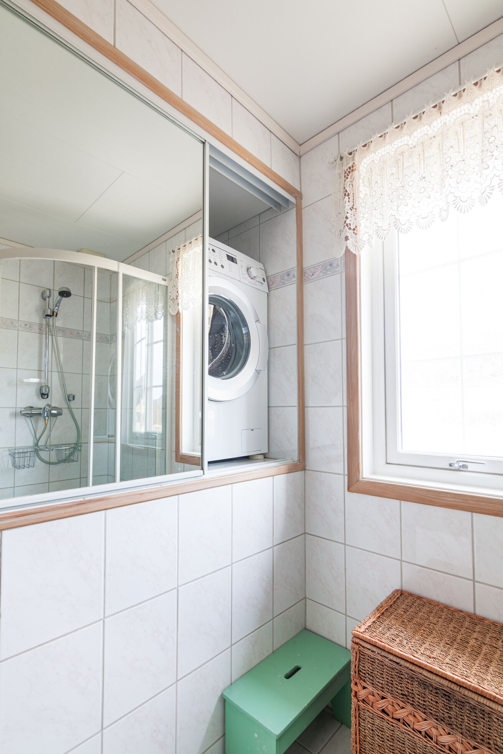 Une buanderie équipée d’un lave-linge, d’une douche et d’une petite marche.