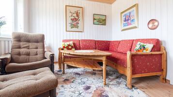 A room with a red sofa, a wooden armchair, a wooden coffee table, and a floral rug.