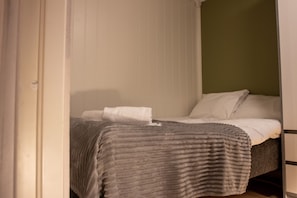 Un dormitorio con cama, mesita de noche y cortina.