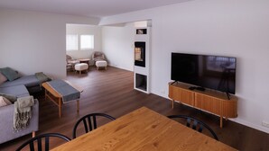 A modern living room with a sofa, ottomans, a wooden table, and a TV.