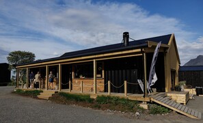 A wooden building with a covered porch, a chimney, and a flag. - Fredly, beautiful home in Fredvang (Flakstad)