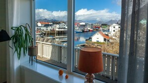 Una habitación con un ventanal que da a un puerto, una planta en maceta y una lámpara en el alféizar.
