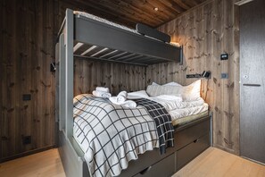 A bunk bed with a headboard, a bedside table, and a wall-mounted light fixture.