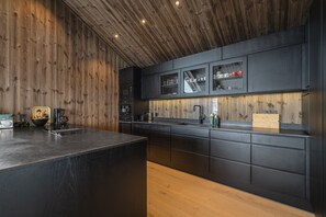 A modern kitchen with wooden paneling, a large island, and built-in appliances.