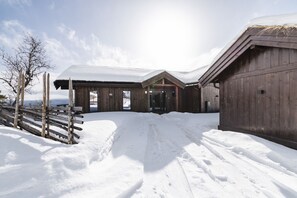 A wooden building with a snow-covered roof, a visible entrance, and a number '95' on the wall.