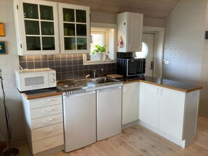 Eine kleine Küche mit weißen Schränken, einer Mikrowelle, einem Toaster und einem Spülbecken.