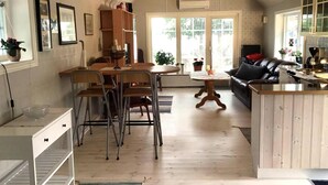 Una cocina amplia con armarios de madera, un comedor con sillas, una isla central y una sala de estar con un sofá.