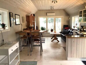 Eine geräumige Küche mit Holzschränken, einem Essbereich mit Stühlen, einer zentralen Kochinsel und einem Wohnbereich mit einer Couch.