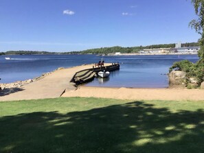 Ein Strand mit einem vor Anker liegenden Boot, sandigem Ufer und freiem Blick auf das Wasser.
