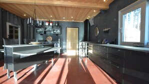 A modern kitchen with a central island, dark cabinetry, and a large window providing natural light.