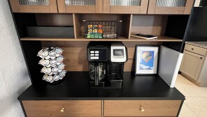 A kitchenette with a coffee maker, a stack of yogurt containers, a framed picture, and a small refrigerator. - Space Coast getaway! The Yellow Sunrise! 2 bed 1 bath Oasis (Merritt Island)