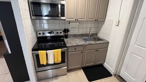 A kitchen with a microwave, stove, sink, and cabinets. - Space Coast getaway! The Yellow Sunrise! 2 bed 1 bath Oasis (Merritt Island)