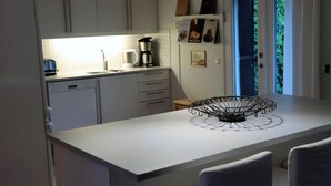 Eine moderne Küche mit weißen Schränken, einer Kaffeemaschine und einem dekorativen Drahtkorb auf der Kücheninsel.