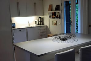 Eine moderne Küche mit weißen Schränken, einer Kaffeemaschine und einem dekorativen Drahtkorb auf der Kücheninsel.