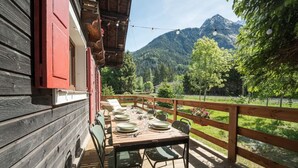 Una terraza de madera con una mesa preparada para comer, con vistas a un paisaje montañoso.