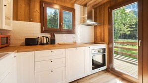 Una cocina con armarios de madera, microondas, hervidor y horno.