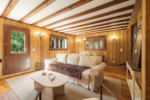 Ein Holzinterieur mit einer Couch, einem Tisch und einem Fernseher.