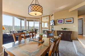 A spacious living area with a large dining table, comfortable seating, a fireplace, and a television. - New Listing! River Views | Hot Tub | Near Mt. Bachelor (Bend)