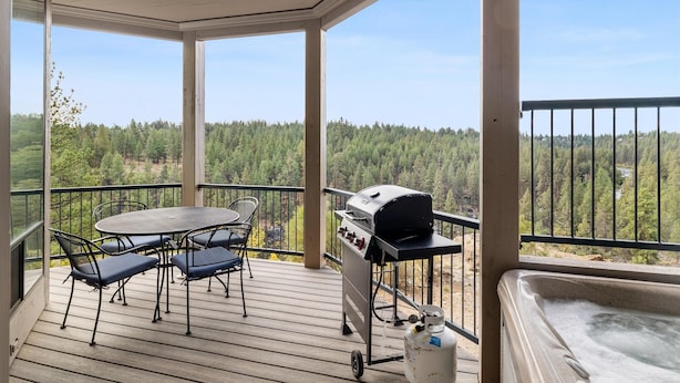 A covered outdoor deck with a table and chairs, a grill, and a hot tub. - New Listing! River Views | Hot Tub | Near Mt. Bachelor (Bend)