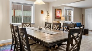 Une salle à manger avec une table et des chaises en bois, un lampadaire et un tableau au mur.