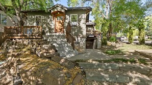 Ein zweistöckiges Haus mit einer Holzterrasse, Steintreppen und einer Steinmauer.