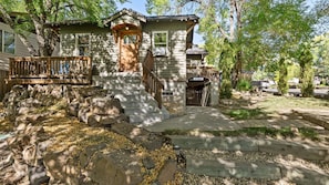 Ein zweistöckiges Haus mit einer Holzterrasse, Steintreppen und einer Steinmauer.