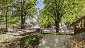 Une rue résidentielle bordée d’arbres, avec un panneau de signalisation et des voitures garées.