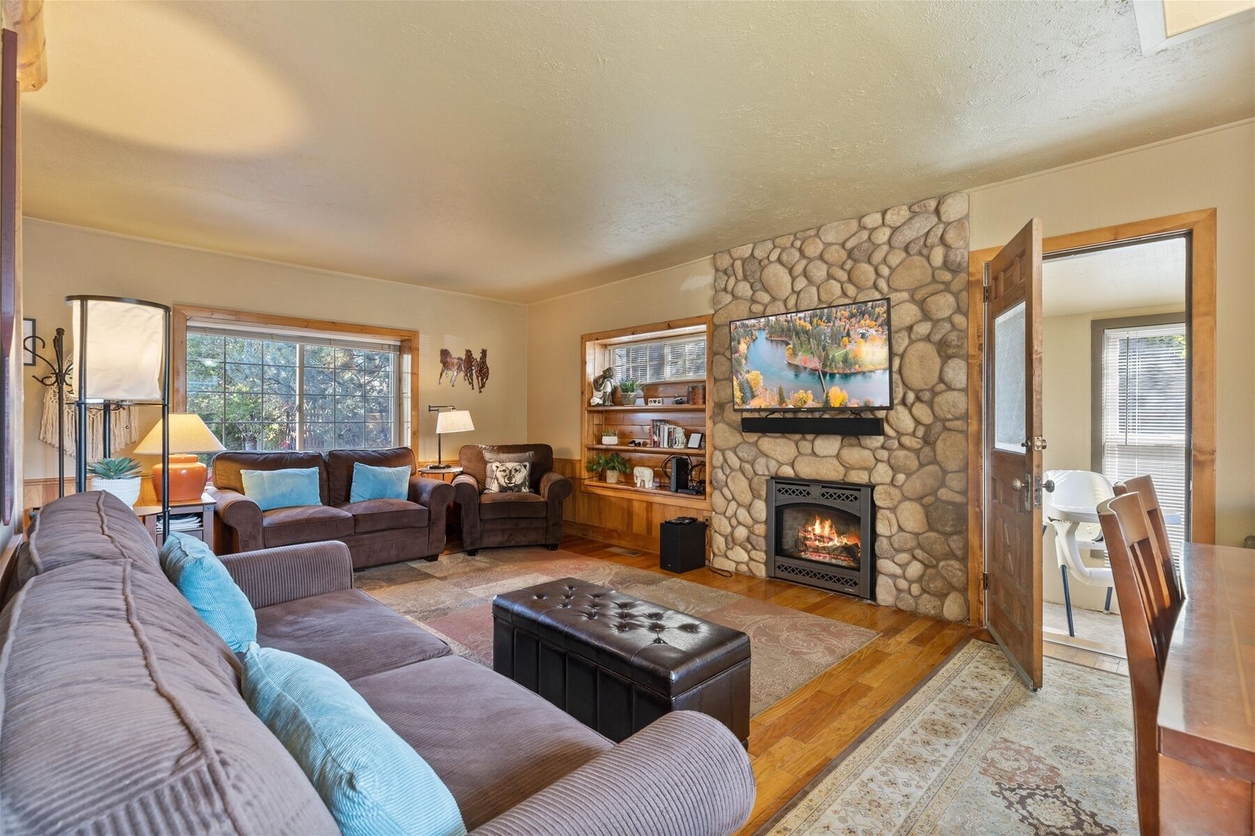 A cozy living room with a stone fireplace, a large sofa, and a bookshelf.