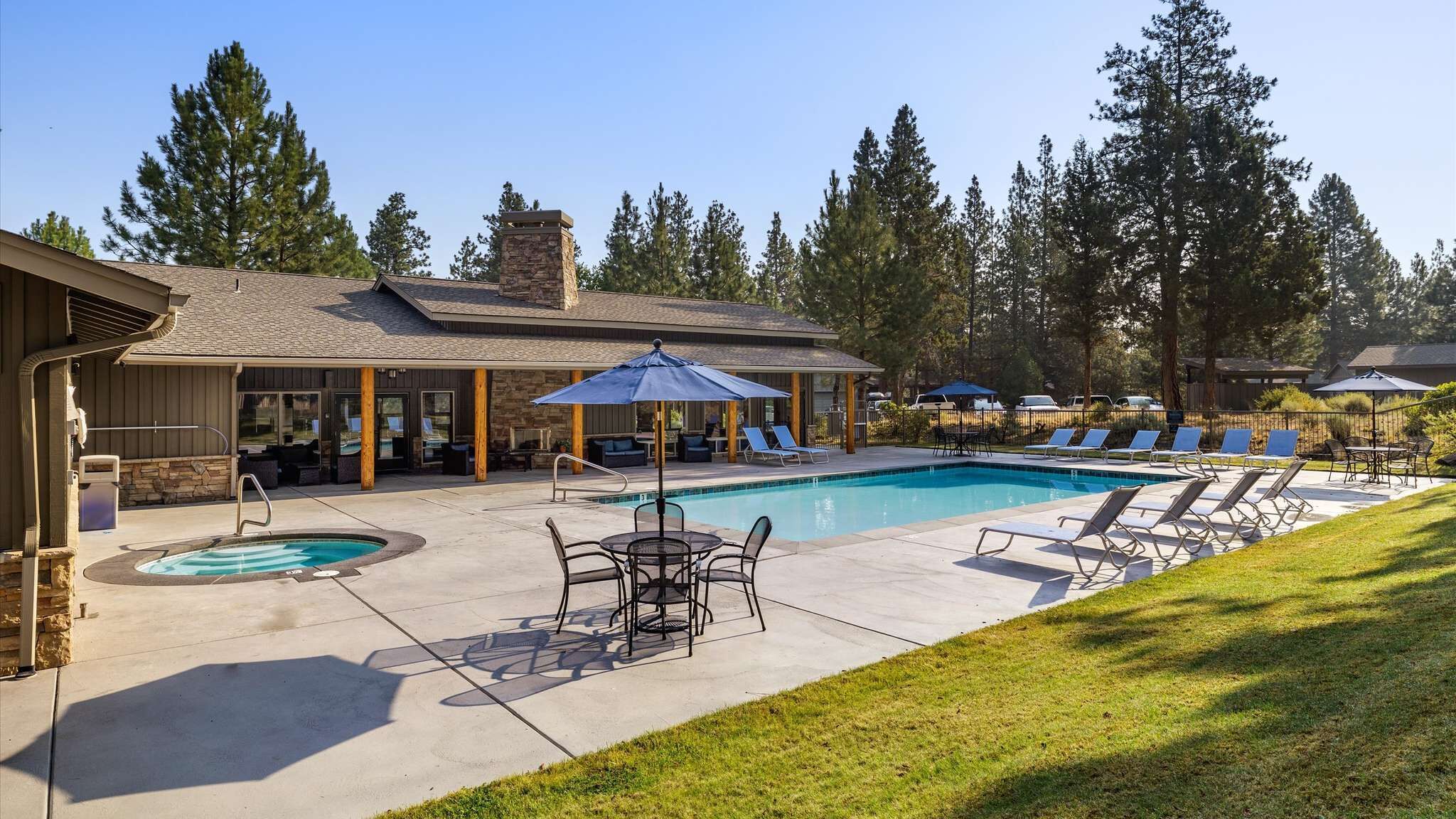 A pool area with lounge chairs, a hot tub, and a covered seating area.