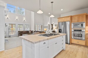 A modern kitchen with a central island, stainless steel appliances, and wooden cabinets. - New! Luxury Forest Home | Arcade Room | Pool - Hot Tub (Bend)