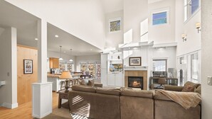 Amplia sala de estar con un sofá seccional grande, una chimenea y una zona de cocina con una mesa de comedor y sillas.