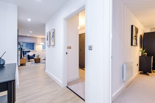 A modern interior with a wooden floor, white walls, and a dark wooden cabinet. - Modern 2BR Apartment Leeds Centre (Leeds)