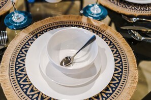 Une table à manger avec une assiette blanche, une cuillère et un verre bleu.